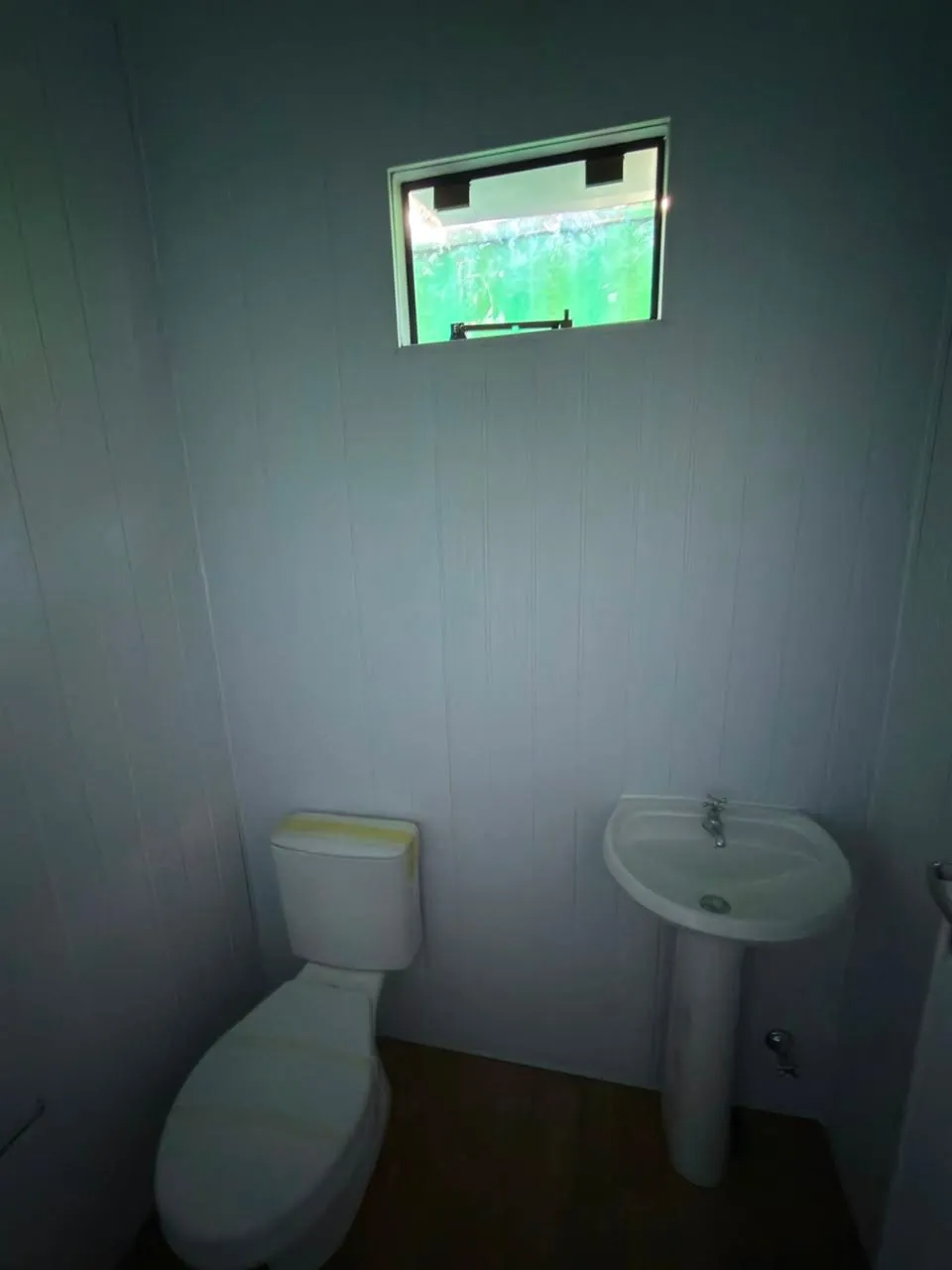 Baño del módulo con inodoro, lavatorio y ventana, revestimiento PVC