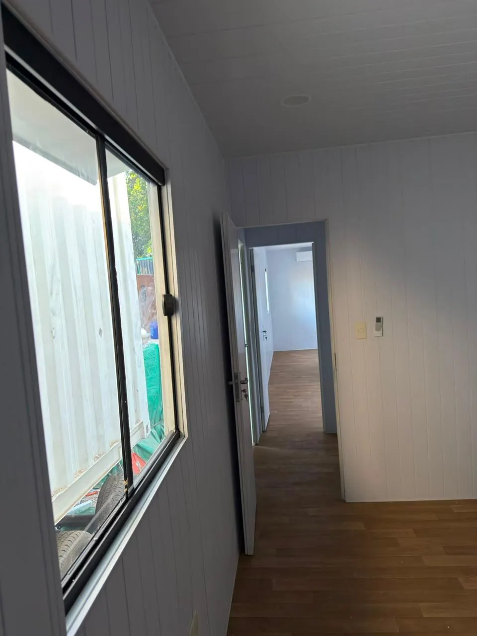 Pasillo interior que conecta las dos oficinas, con PVC blanco, LED embutida y piso vinílico