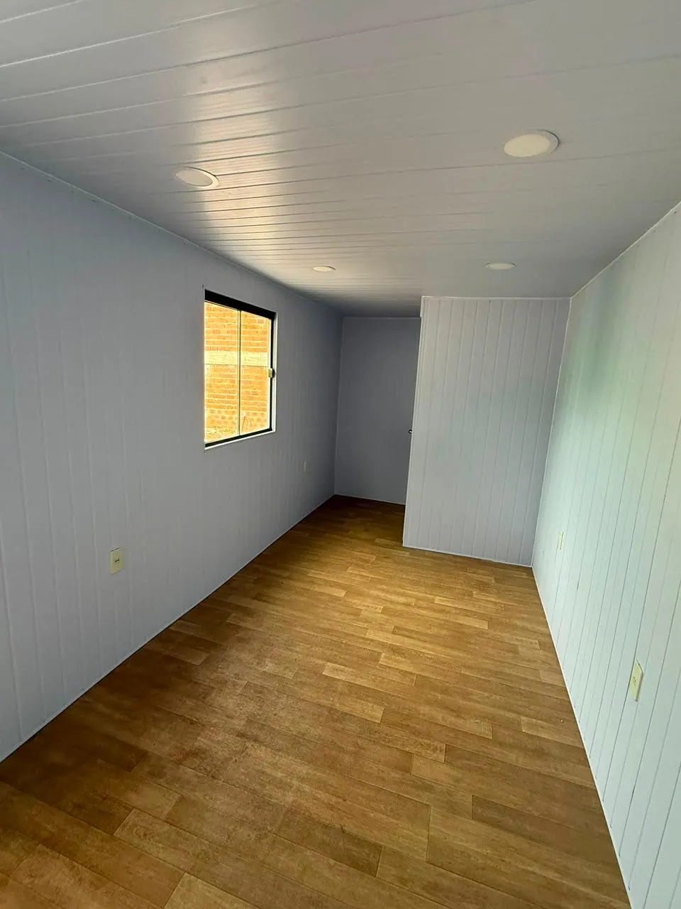 Interior vacío de la oficina 20 pies con paredes y cielorraso en PVC blanco y piso vinílico símil parquet