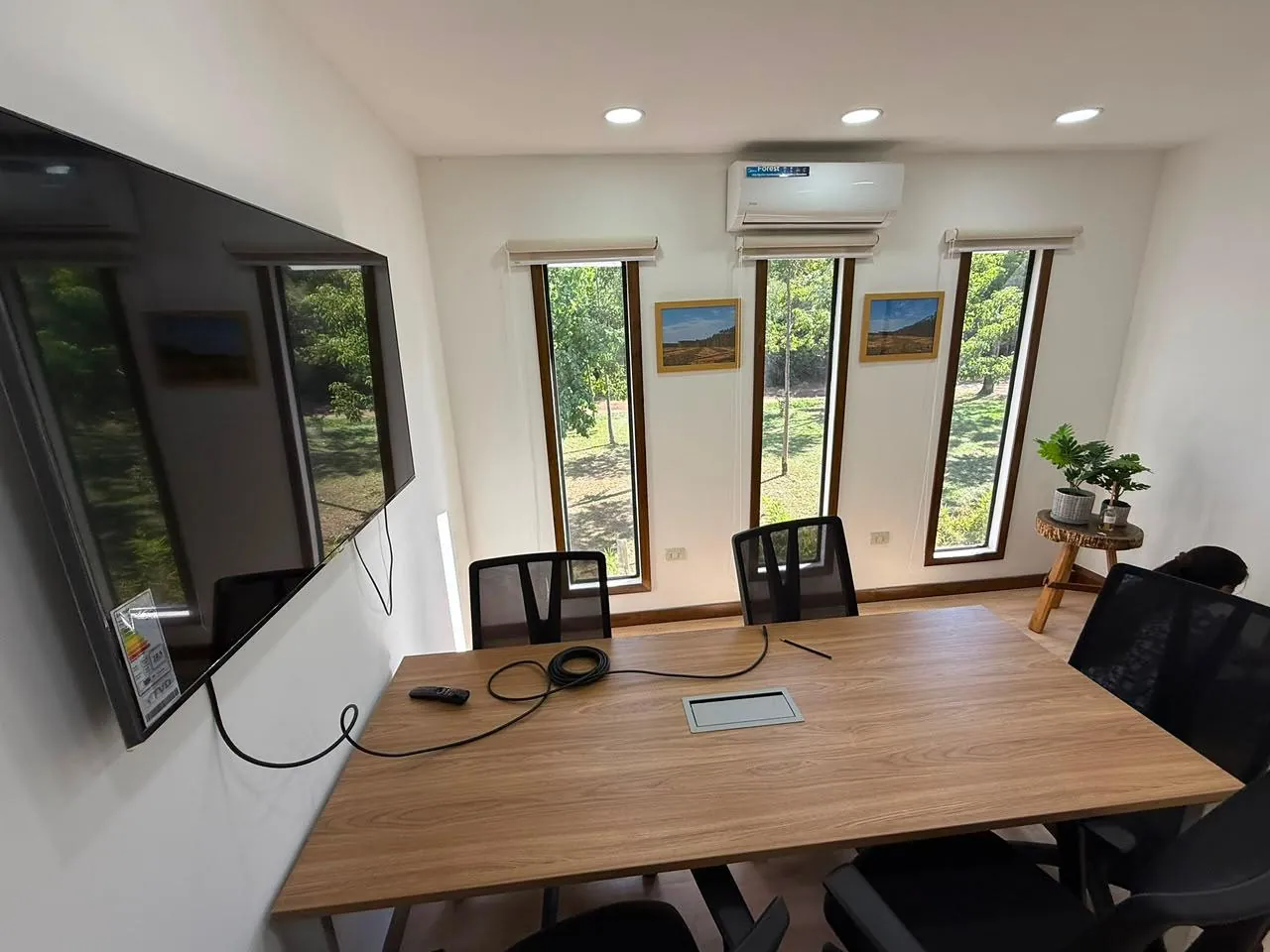 Sala de reuniones con mesa de directorio, sillas ejecutivas, TV y ventanales