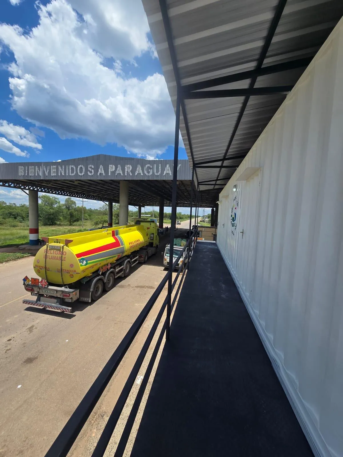 Puesto de control desde la pasarela, con el cartel Bienvenidos a Paraguay y un camión cisterna