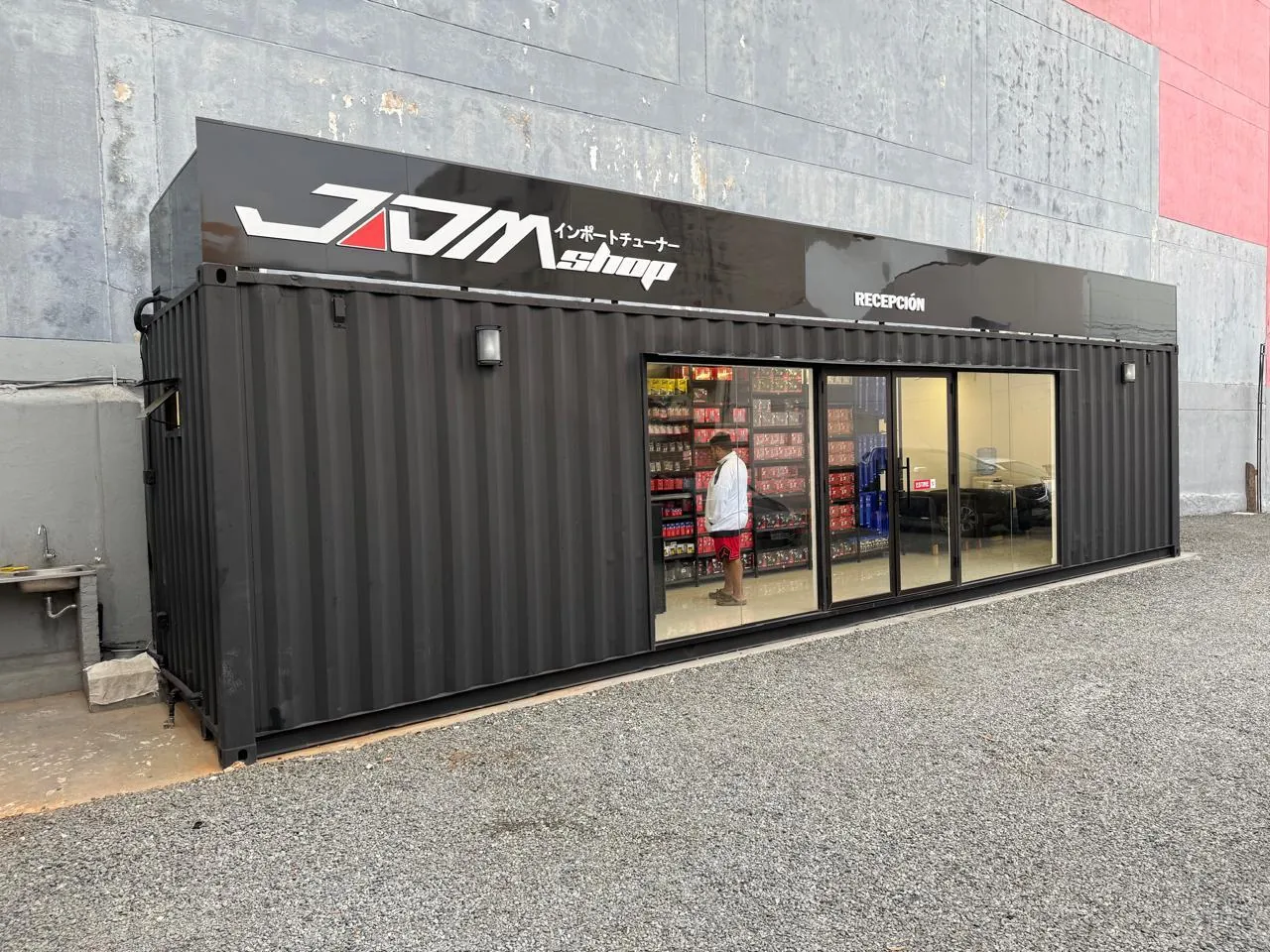 Fachada del showroom contenedor desde un ángulo cerrado, con frente acristalado