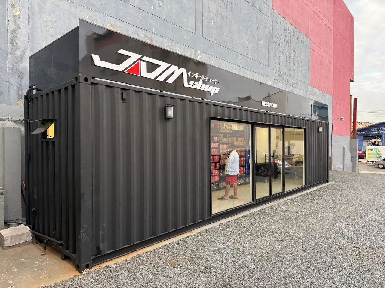Showroom contenedor 40 pies instalado, con contexto de patio industrial de fondo
