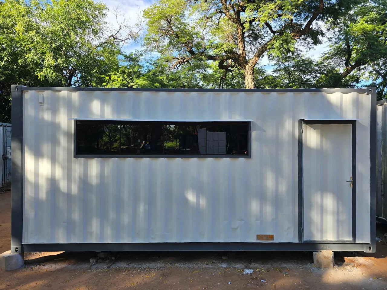 Vestuario en contenedor de 20 pies, fachada frontal con ventana y puerta de acceso