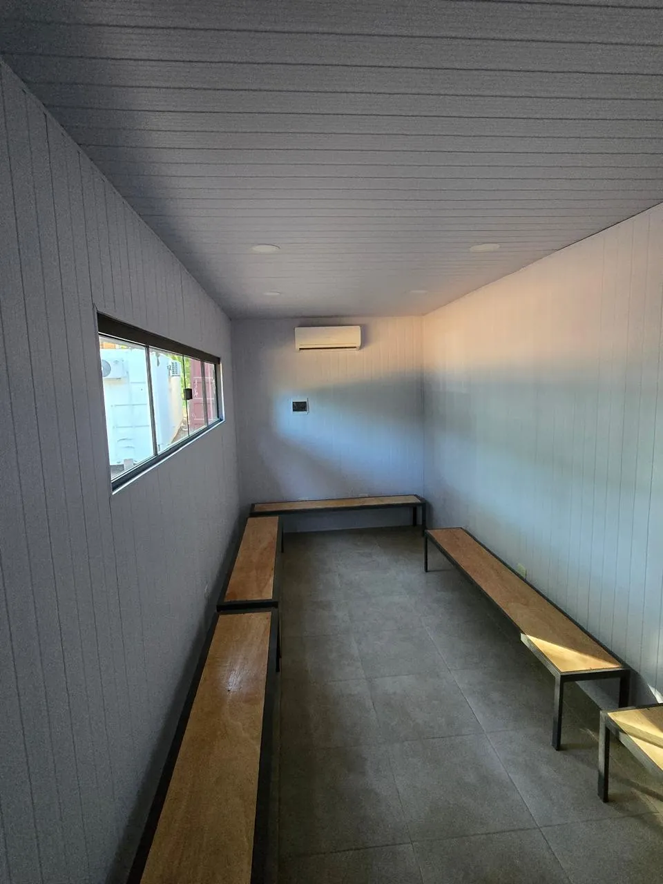 Interior del vestuario con bancos, revestimiento PVC gris y LED embutida