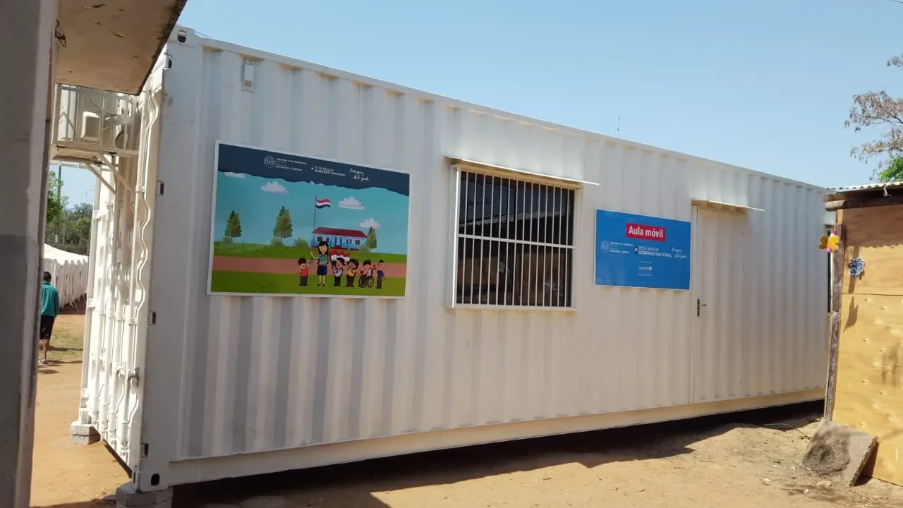Aula móvil en contenedor blanco con mural, para uso institucional y educativo