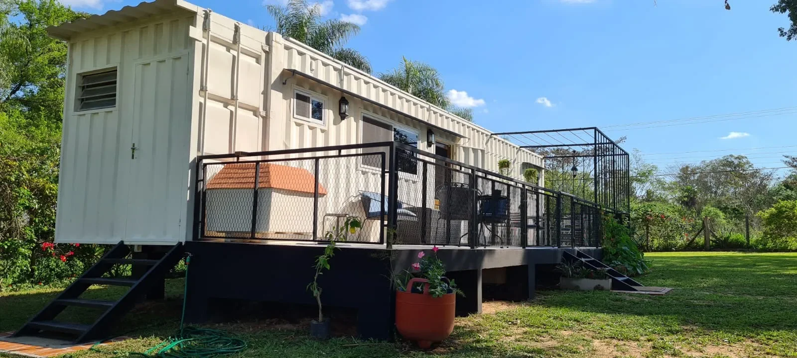 Cabaña en contenedor color crema elevada, con deck y baranda