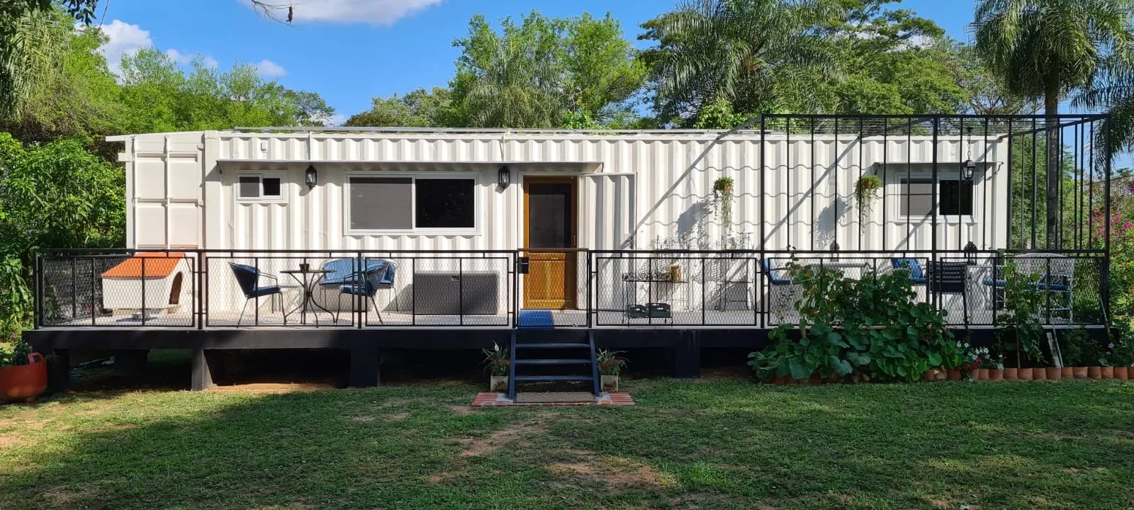 Cabaña blanca en contenedor con deck amplio y puerta de madera