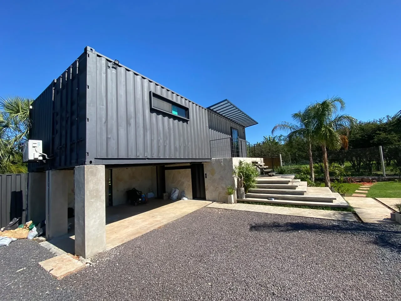 Casa de dos plantas en contenedor pintada de negro con carport
