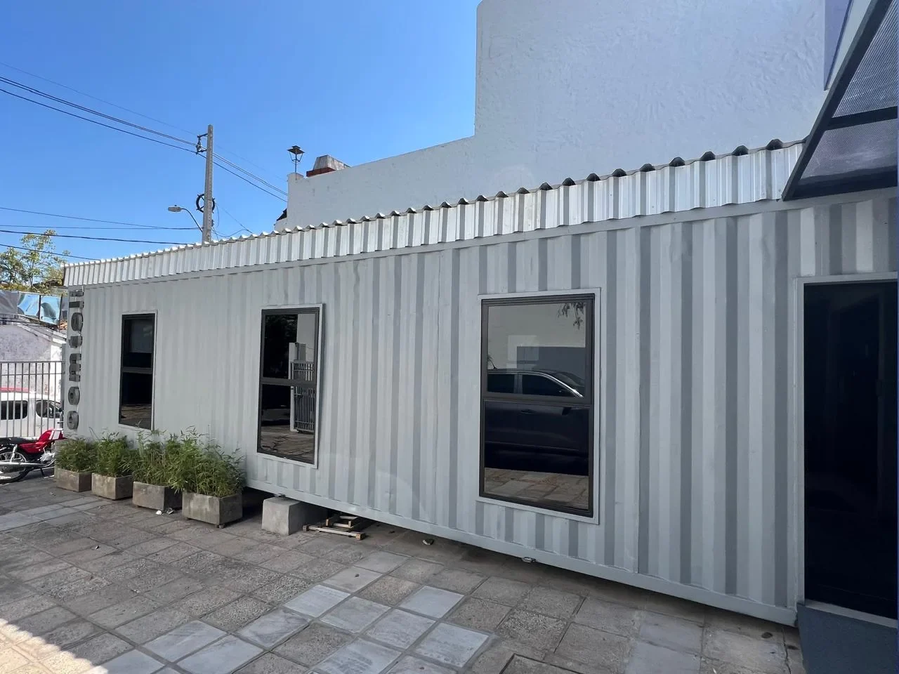 Oficina comercial en contenedor para Comtel, con ventanas espejadas y frente vidriado