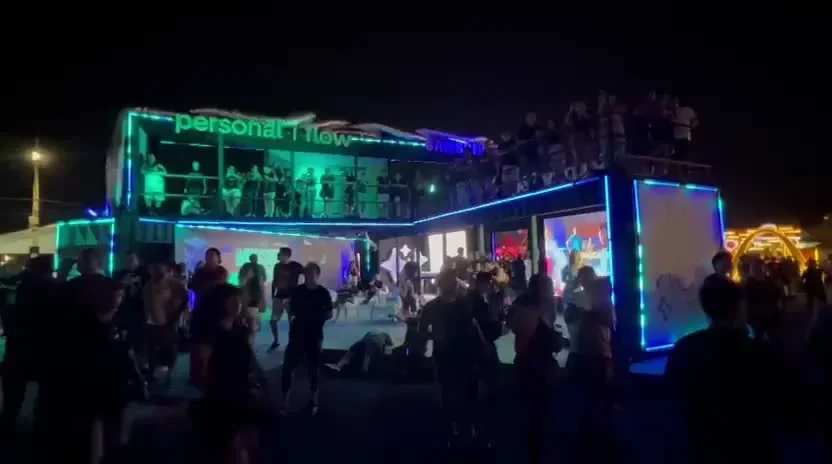 Showroom de dos plantas en contenedor de Personal Flow y Samsung con LED de noche y multitud en el evento.